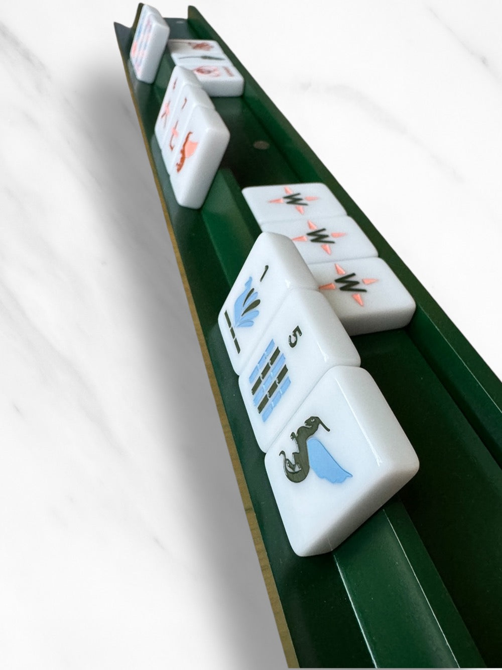 Set of four mahjong racks and pushers on a sleek green board displaying tiles.