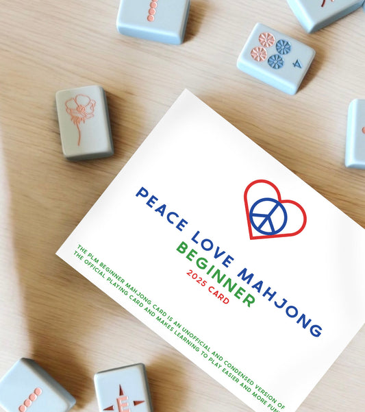 2025 Beginner Peace Love Mahjong Card on wooden surface surrounded by mahjong tiles.