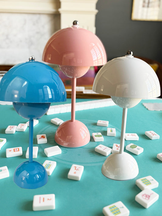 Retro Flower Bud Lamp in white, blush pink, and blue on a mahjong table.