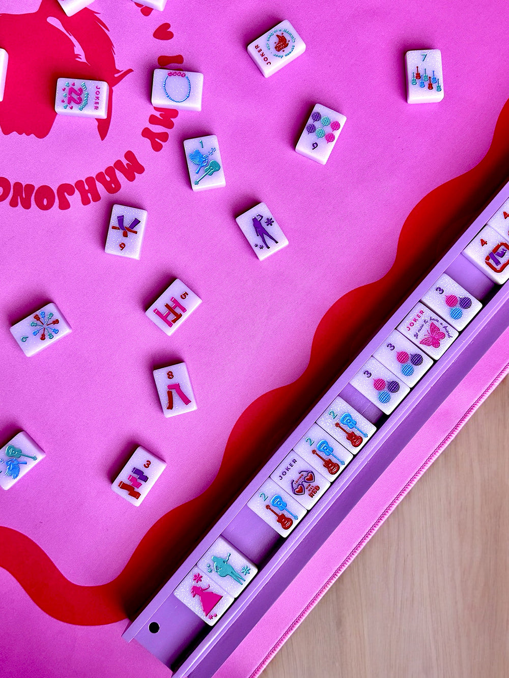 mahjong rack and colorful tiles on a pink table