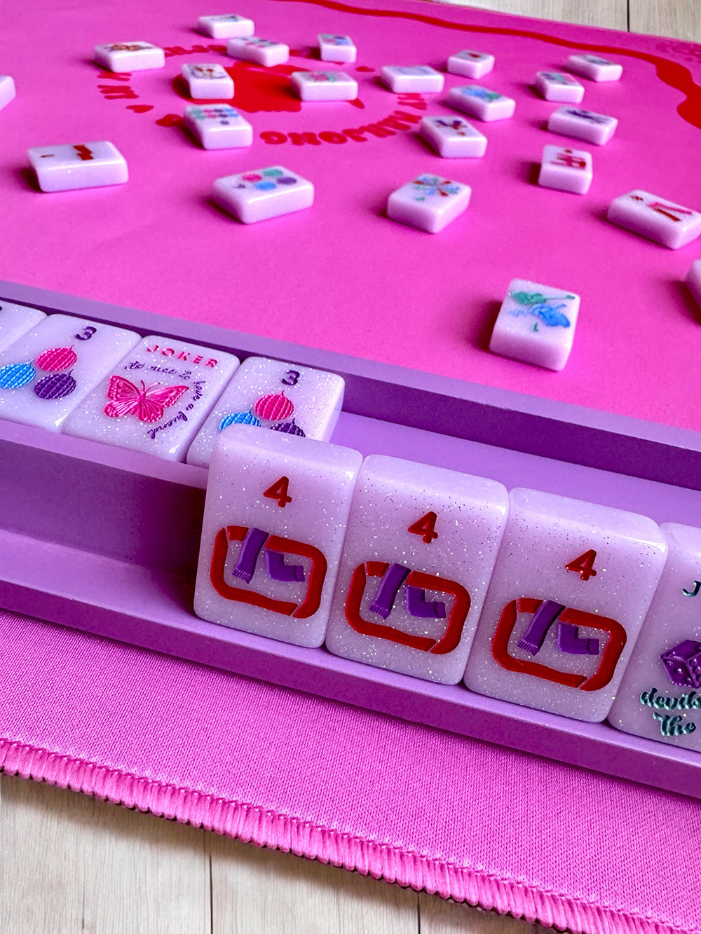 Mahjong racks and pushers set in use with pink tiles on a game table.