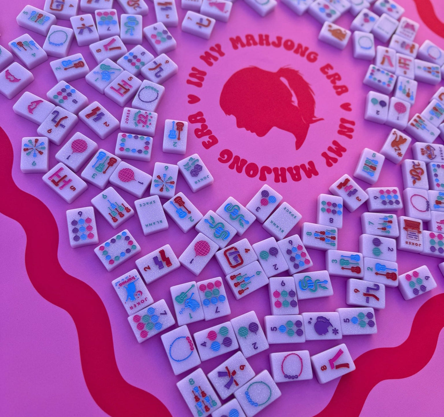 Tiles from Taylor's Tiles Mahjong Set on a pink mat featuring colorful designs and icons.