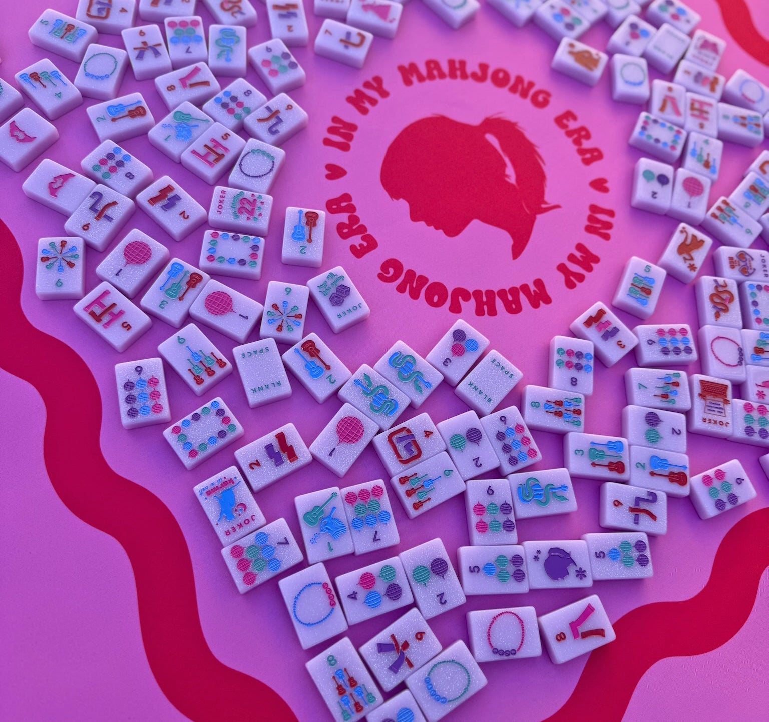 Tiles from Taylor's Tiles Mahjong Set on a pink mat featuring colorful designs and icons.