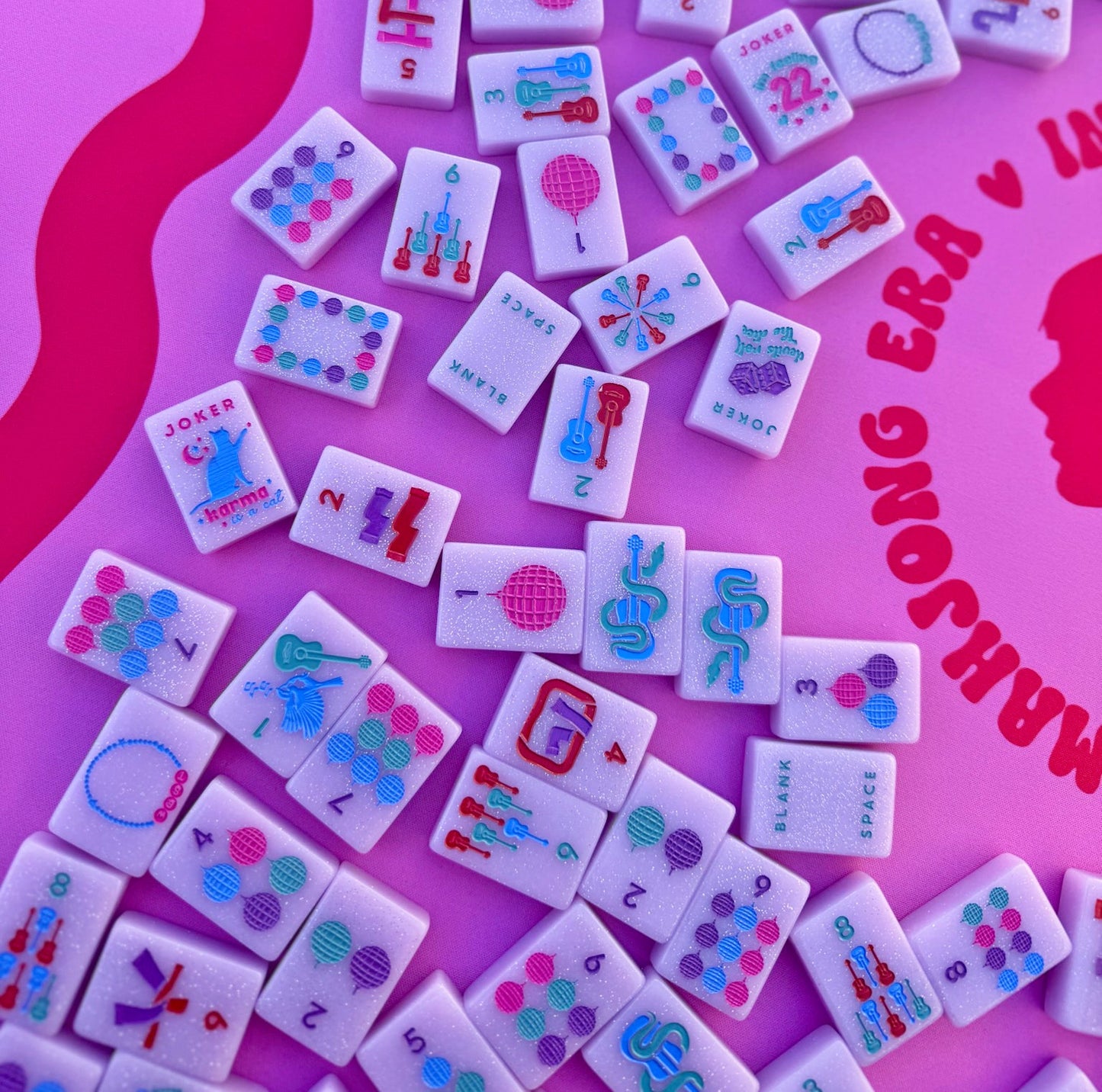 Tiles from Taylor's Tiles Mahjong Set with colorful designs on a pink background.