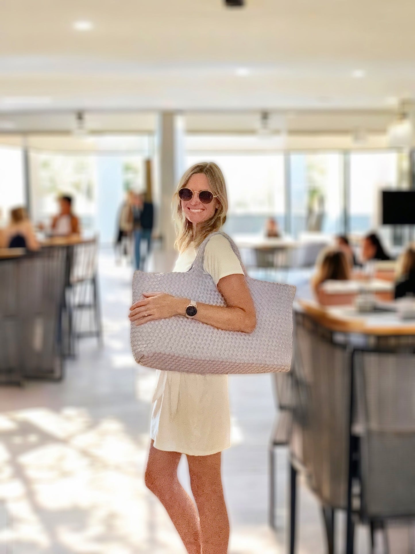Woman holding Woven Mahjong Carryall in a light, modern space.