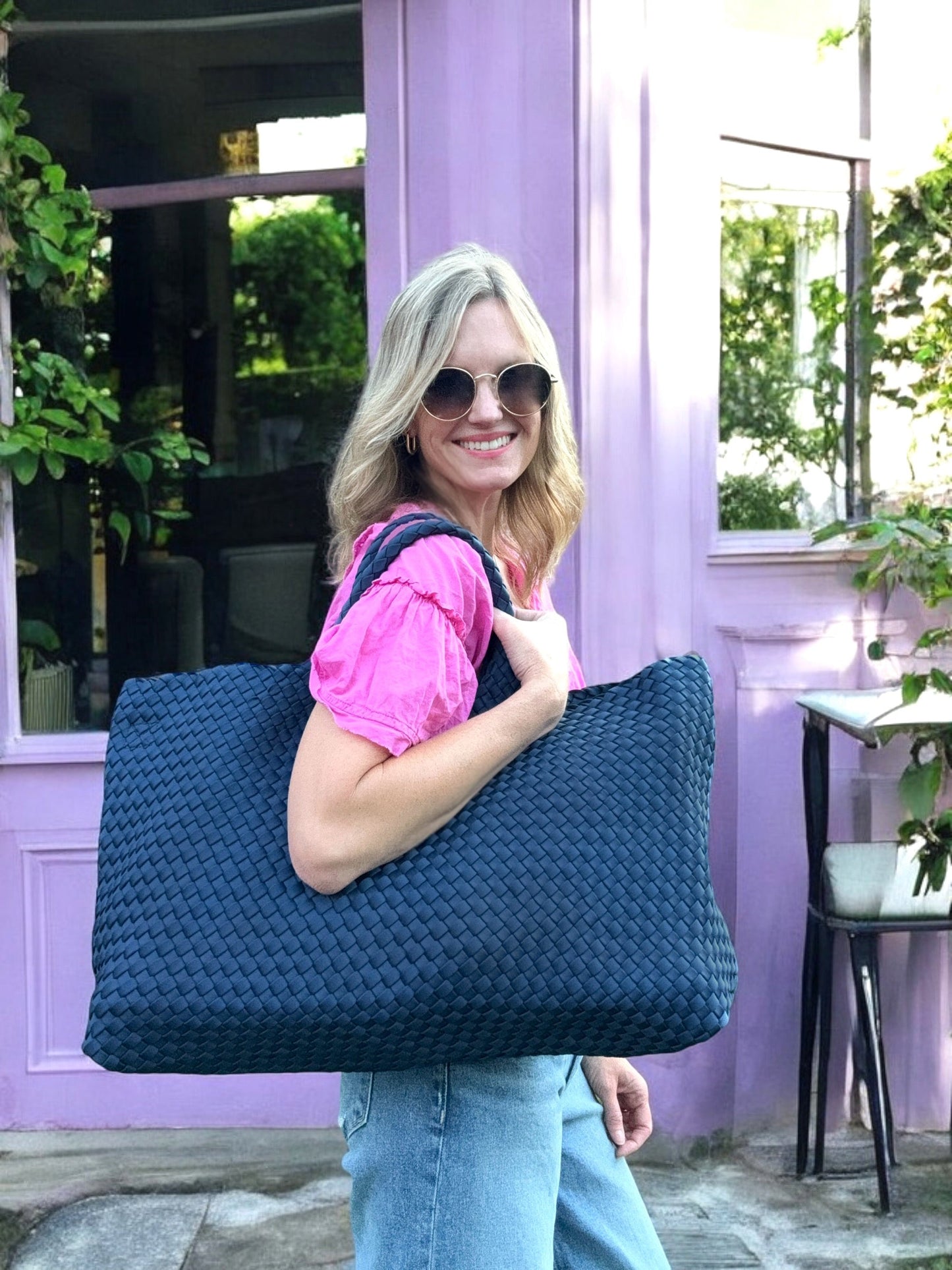 Woven neoprene mahjong carryall in navy worn by woman.