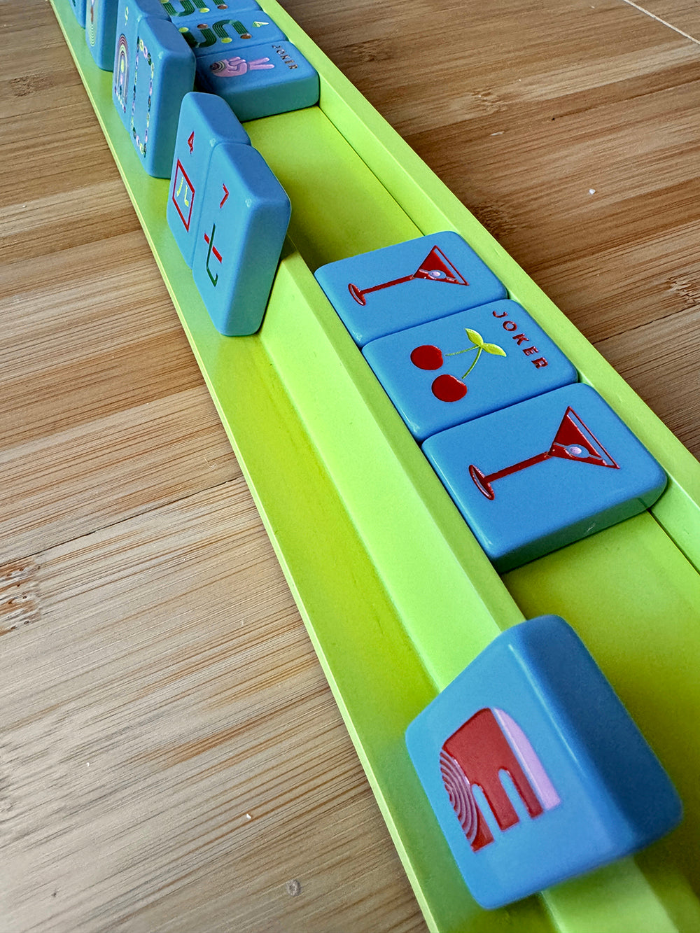 Mahjong racks and pushers set on wooden table showcasing tiles in vibrant colors.