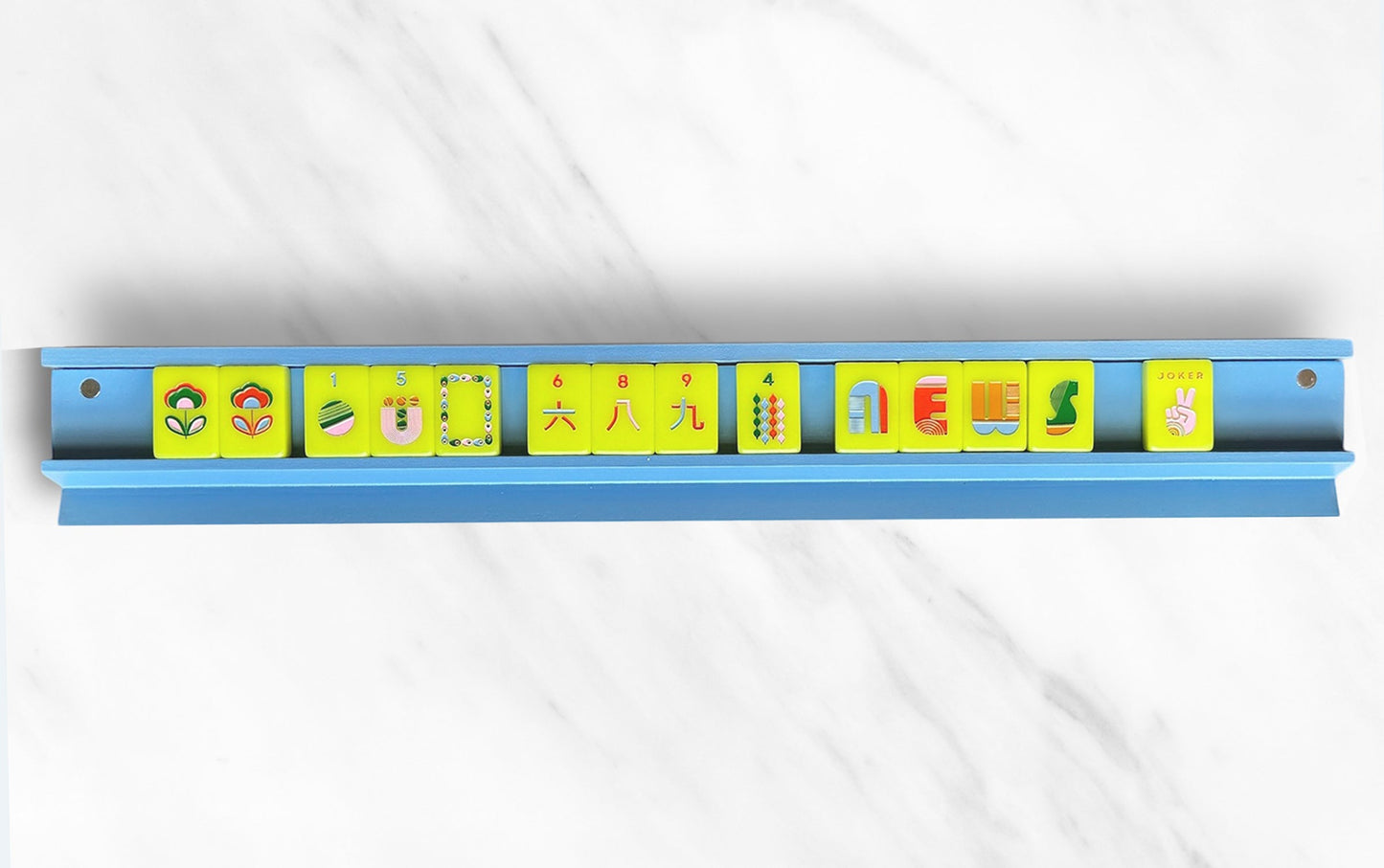 Mahjong rack with colorful tiles on a blue surface.